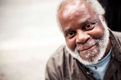 Close up of man wearing brown shirt with a white beard smiling