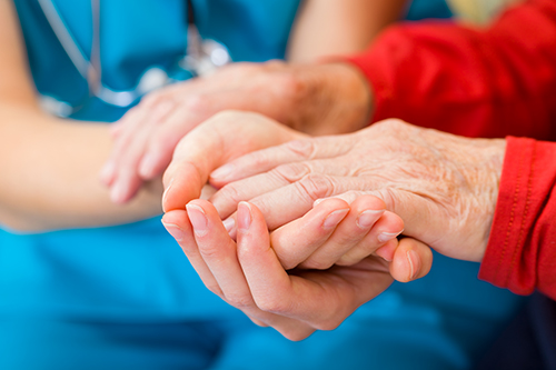 Close up of nurse and female patient holding hands