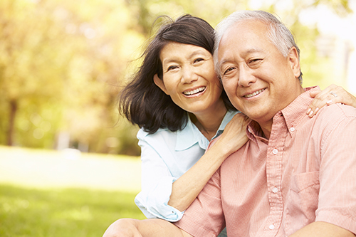 Asian couple sitting outside smiling together